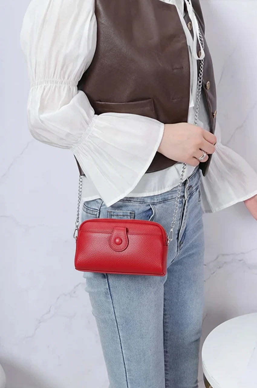 Model wearing the red leather dual-zip crossbody bag with a silver chain, demonstrating size and fit.