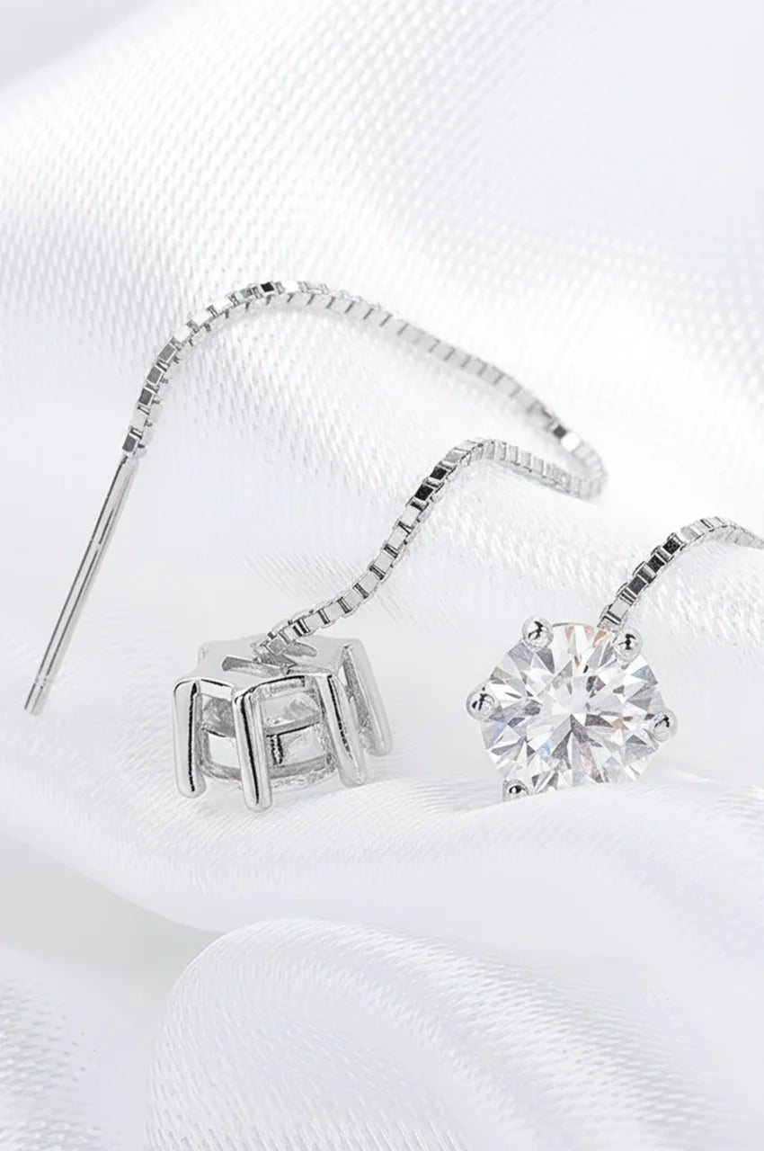 Macro shot of round brilliant cut moissanite stone in silver prong setting attached to a box chain.