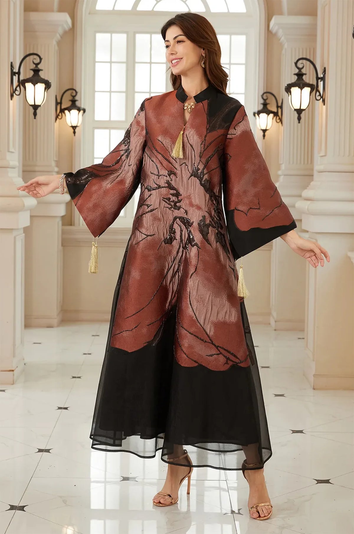 Model posing in the Naeli Red flowy kaftan with a rustic floral print in a bright architectural setting.