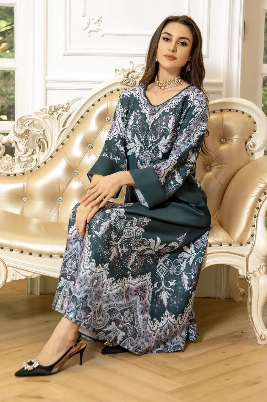 Lifestyle shot of model sitting in Narya emerald green kaftan highlighting hemline details.