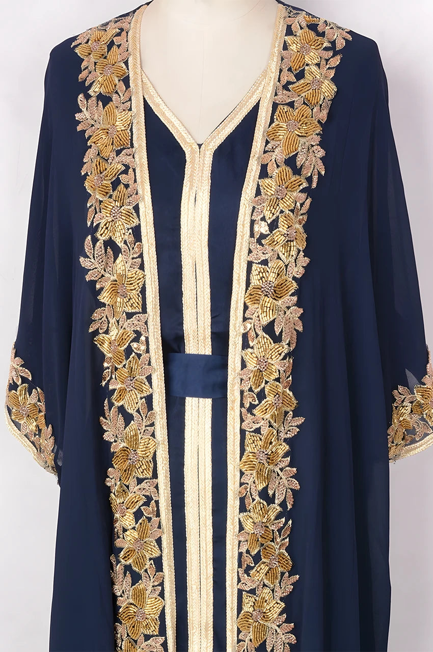 Detailed shot of hand-applied gold floral embroidery on the bodice of a navy blue and gold kaftan.