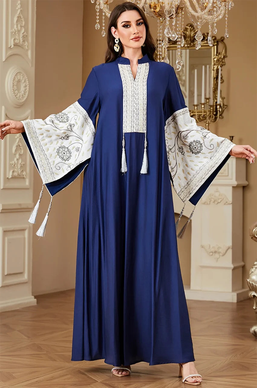 Medium shot of the Nairi navy blue kaftan with arms extended to display the detailed white floral embroidery on the sleeves
