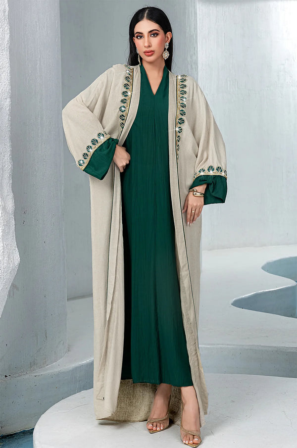 Fashion pose highlighting the wide sleeves and contrasting emerald green cuffs of the Ameline beige kaftan dress by Naylara.