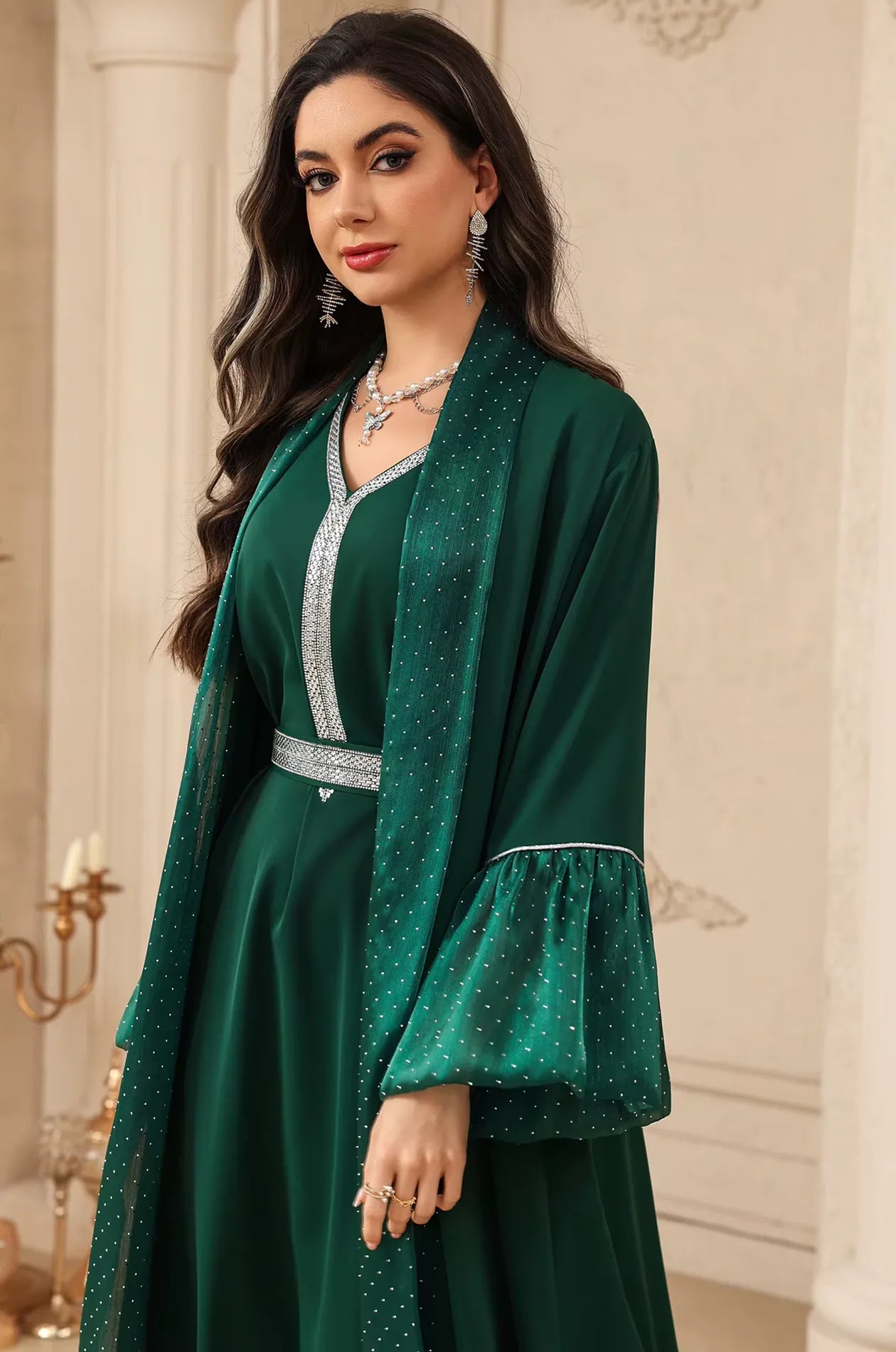 Side profile of the Auris Green solid color Kaftan by Naylara featuring rhinestone-embellished ruffled sleeves and a belted waist.