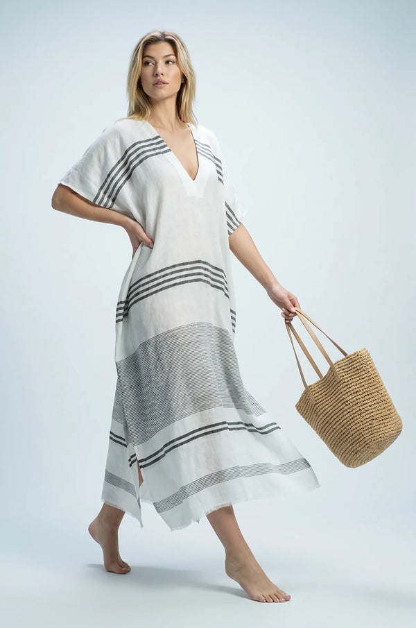 Naylara Dalia beach kaftan styled with straw tote bag — white striped maxi kaftan resort look
