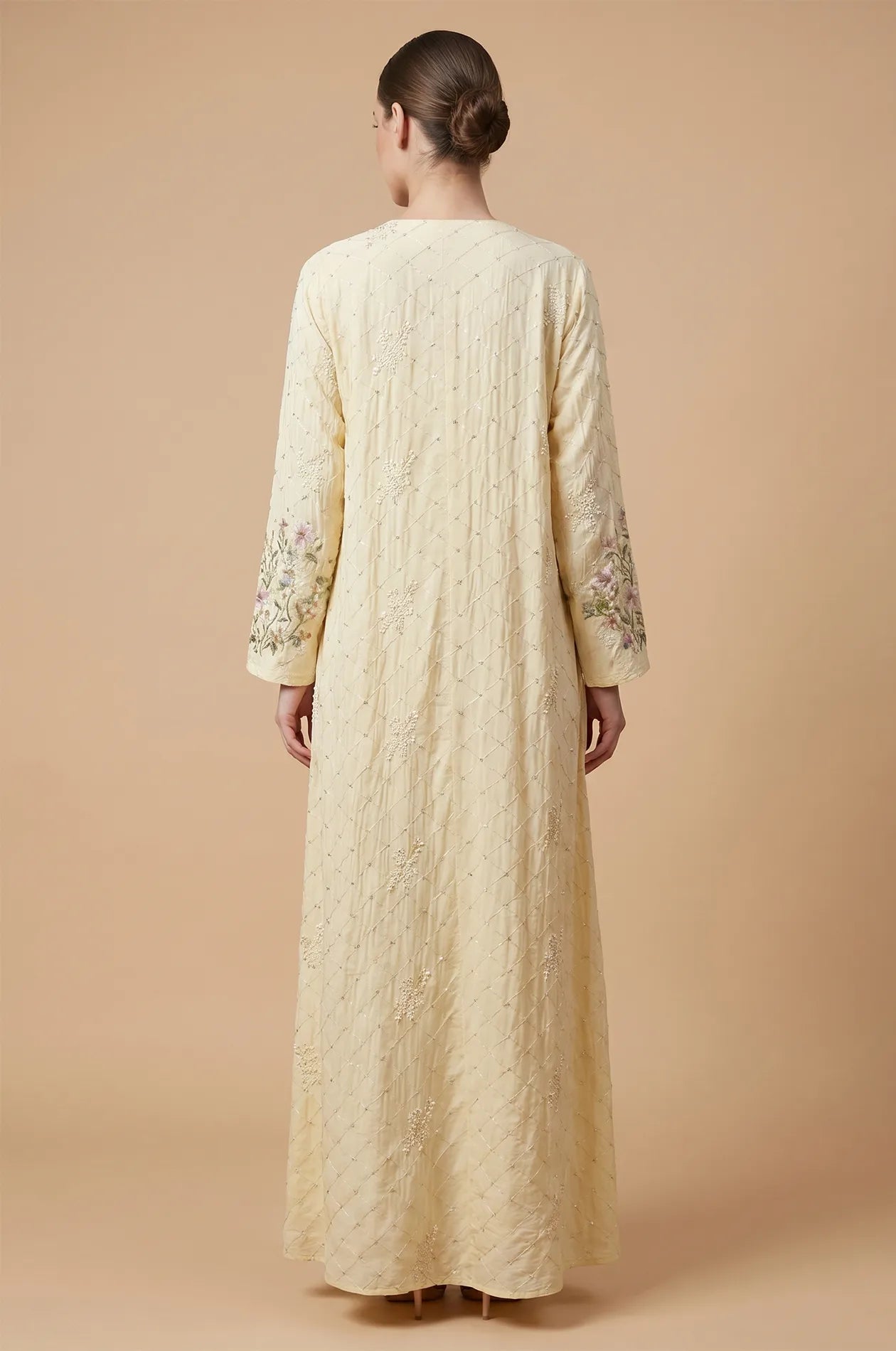 Back view of the beige Equis modest kaftan showing the floor-length drape and textured fabric.