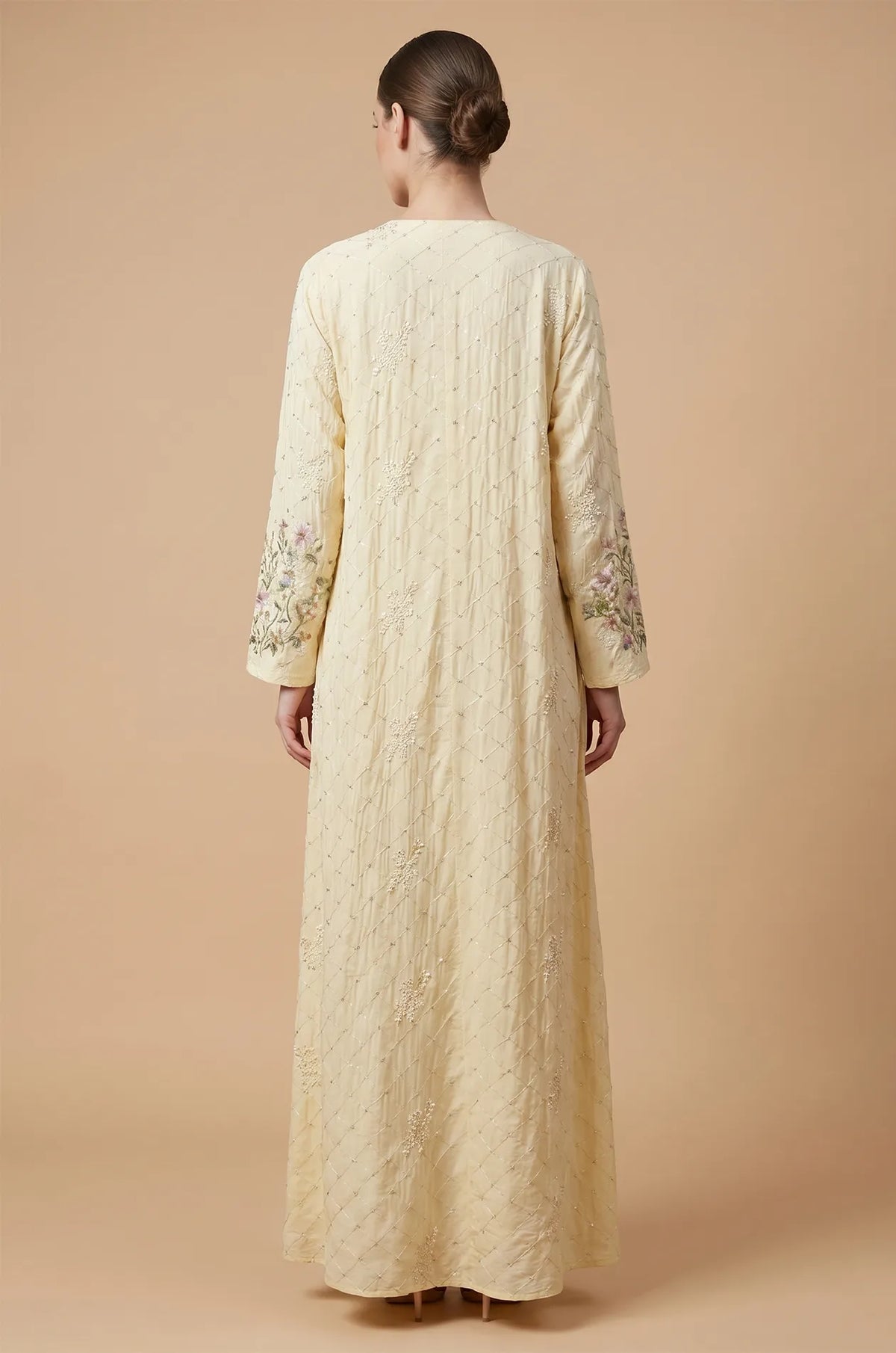 Back view of the beige Equis modest kaftan showing the floor-length drape and textured fabric.