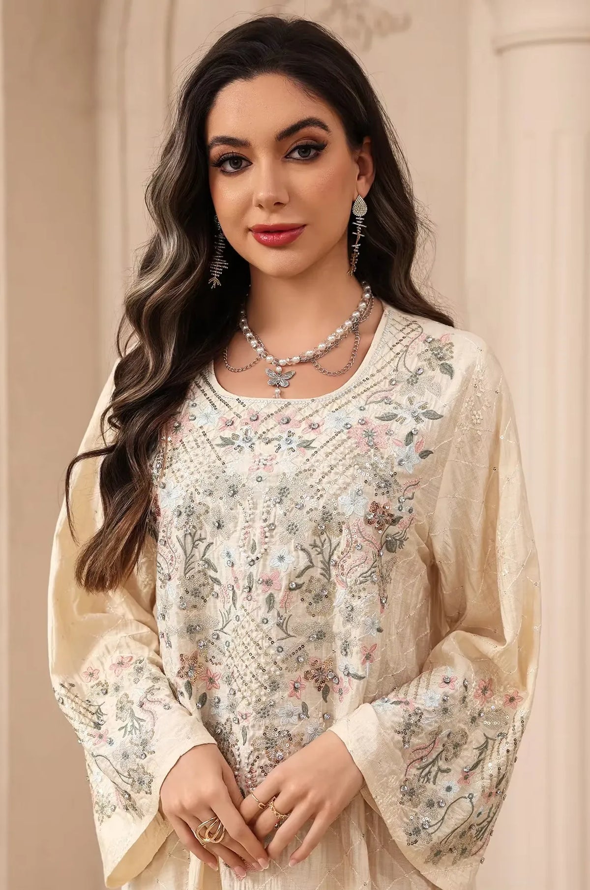Detailed view of the beaded neckline and multi-colored floral embroidery on the beige Equis modest kaftan.