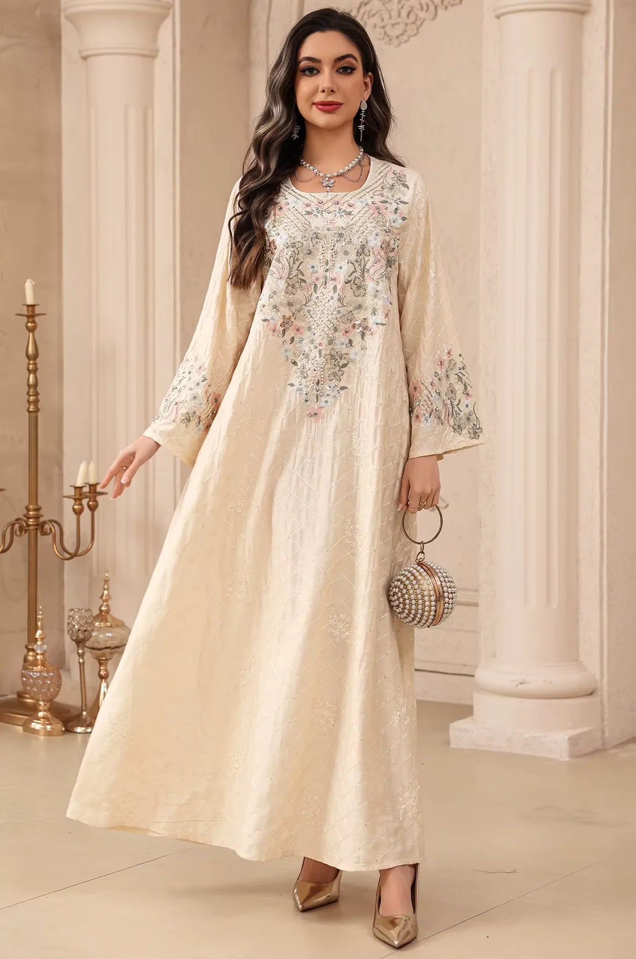 Elegant beige Equis modest kaftan styled with a spherical pearl evening bag in a luxury setting.