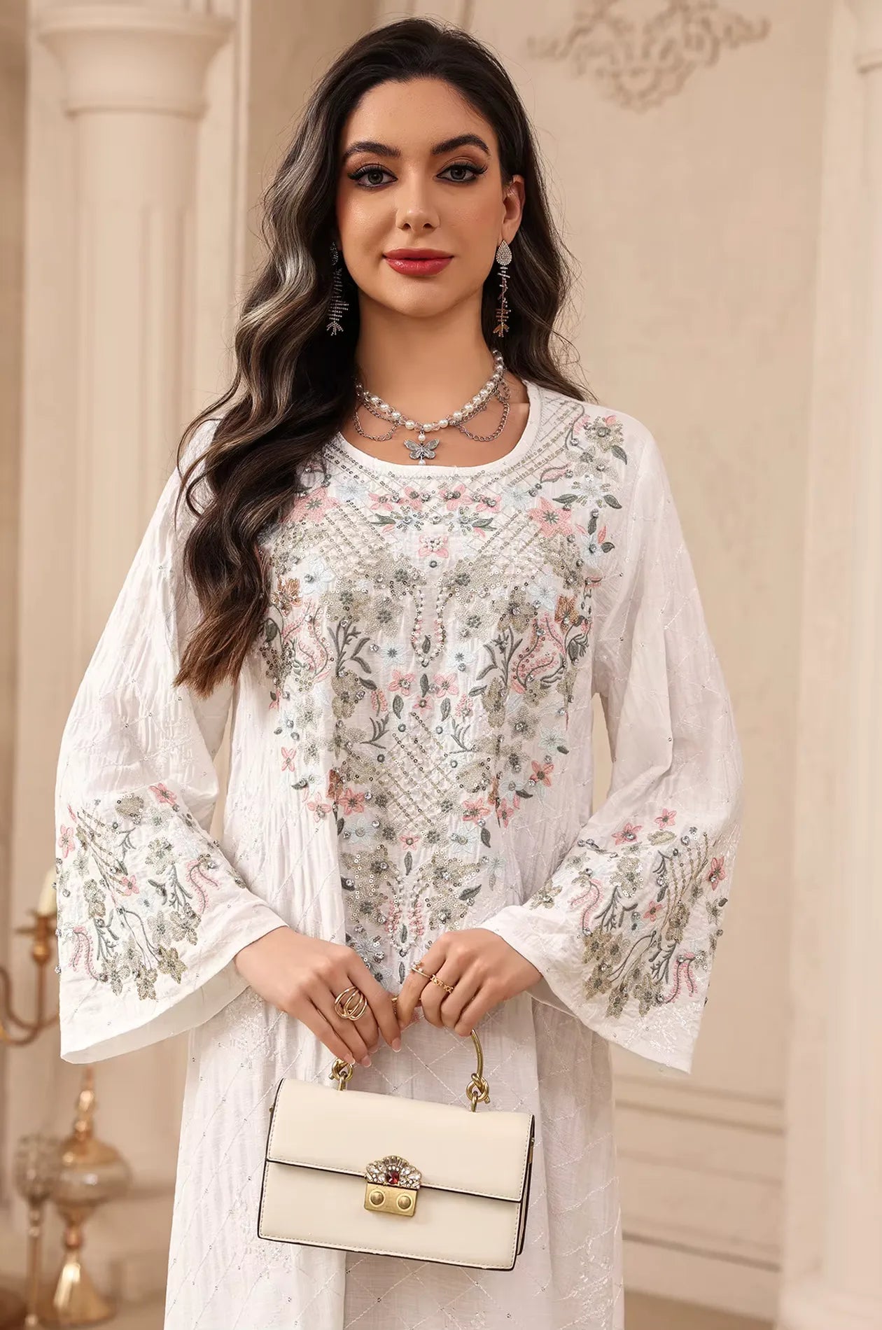 Close-up of the intricate floral threadwork and shimmering rhinestones on the white Equis modest kaftan.