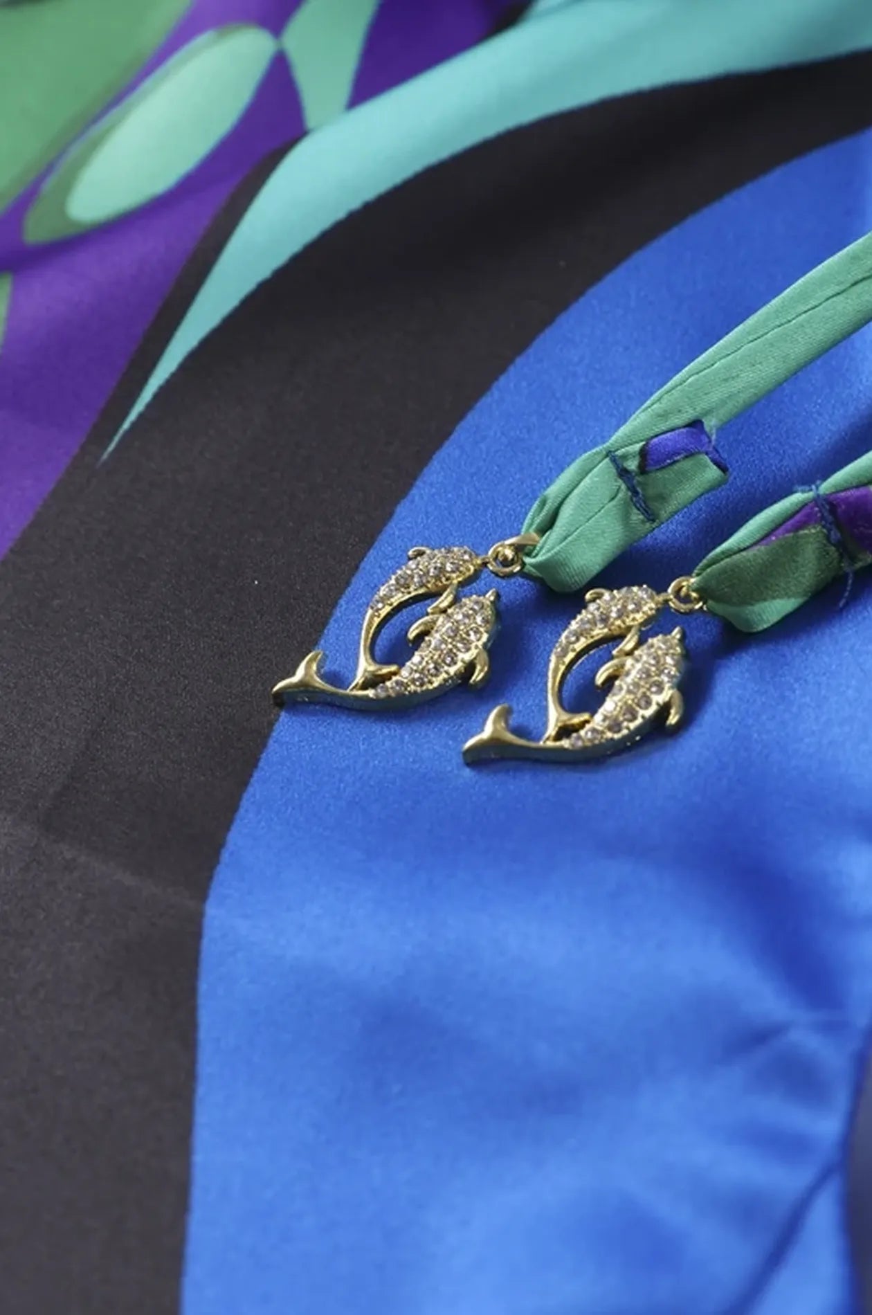 Detail of rhinestone dolphin charms on tassel tie of Naylara Erica blue satin kaftan