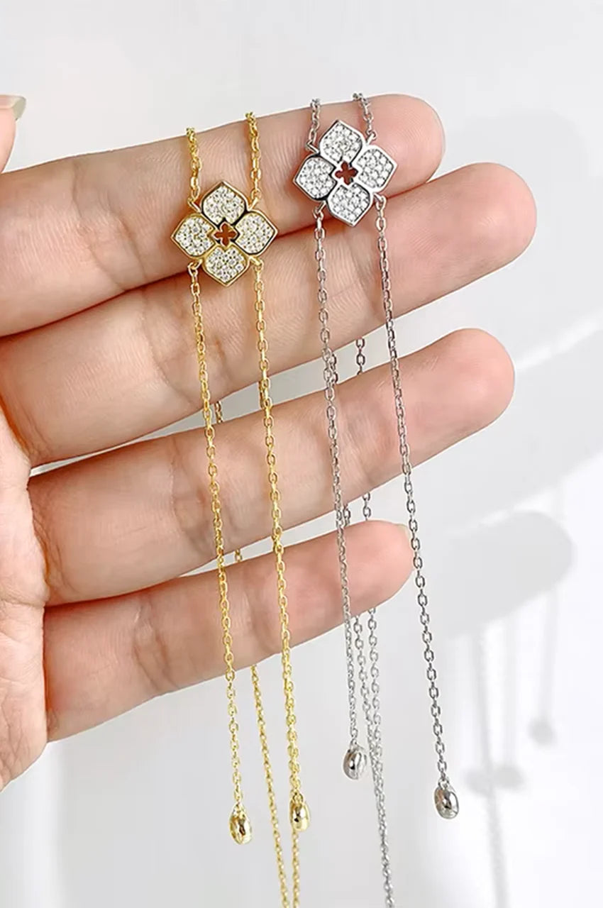 Hand holding gold and silver floral Y-necklaces to show scale and sparkle