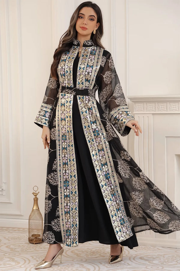 A model posing in the black Gienah chic kaftan from Naylara, highlighting the movement of the sheer floral-patterned fabric.