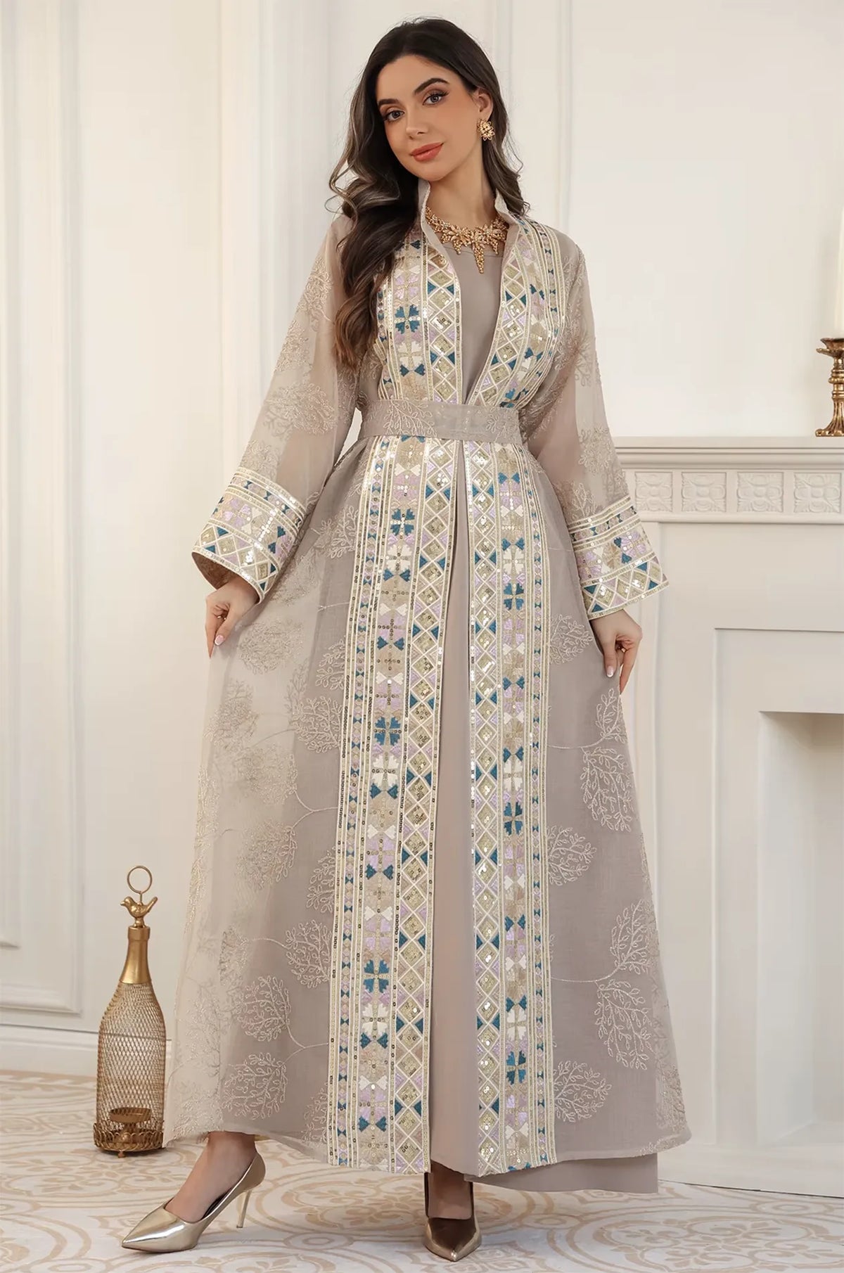 A model posing in the full-length Gienah chic kaftan in apricot beige, emphasizing the elegant drape and craftsmanship.