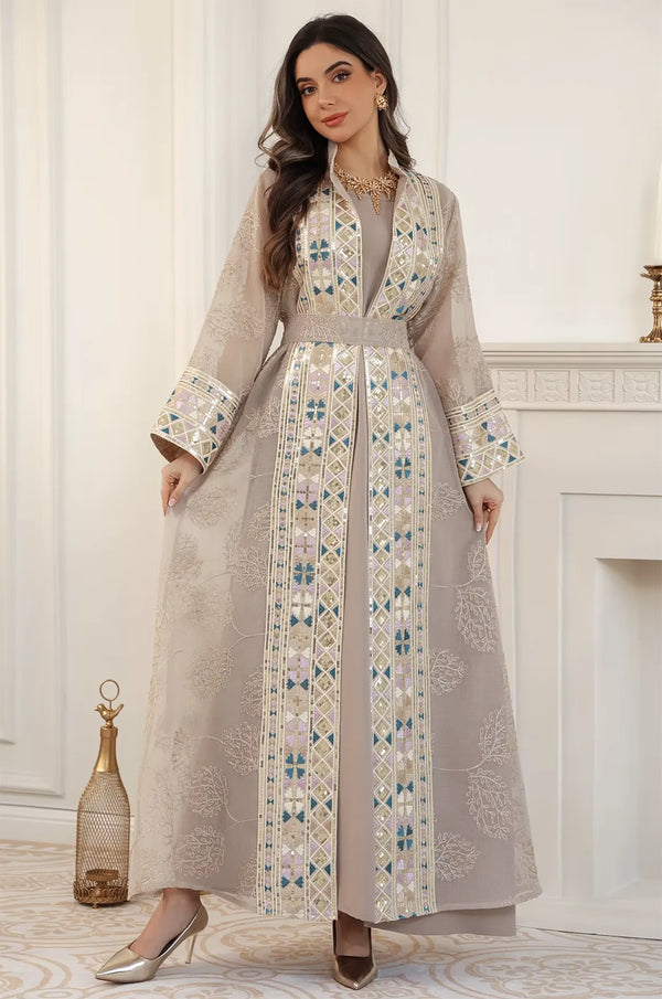A model posing in the full-length Gienah chic kaftan in apricot beige, emphasizing the elegant drape and craftsmanship.