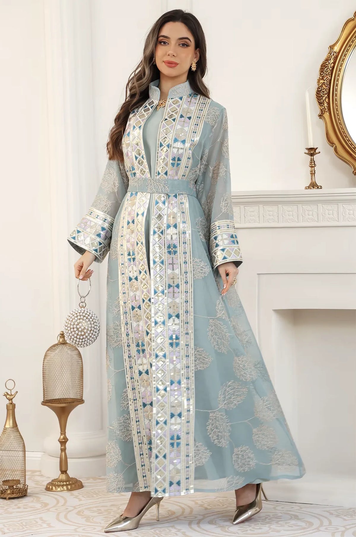 Model styled in the light green Gienah chic kaftan standing by a white fireplace, perfect for high-end formal events.
