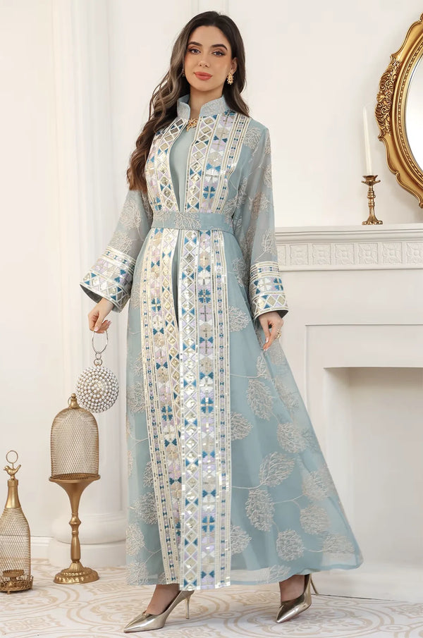 Model styled in the light green Gienah chic kaftan standing by a white fireplace, perfect for high-end formal events.