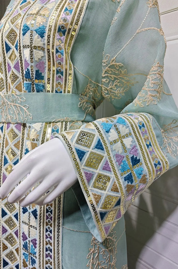 Macro shot of the Gienah light green chic kaftan showing hand-placed rhinestones and geometric sequin borders on the sleeve.