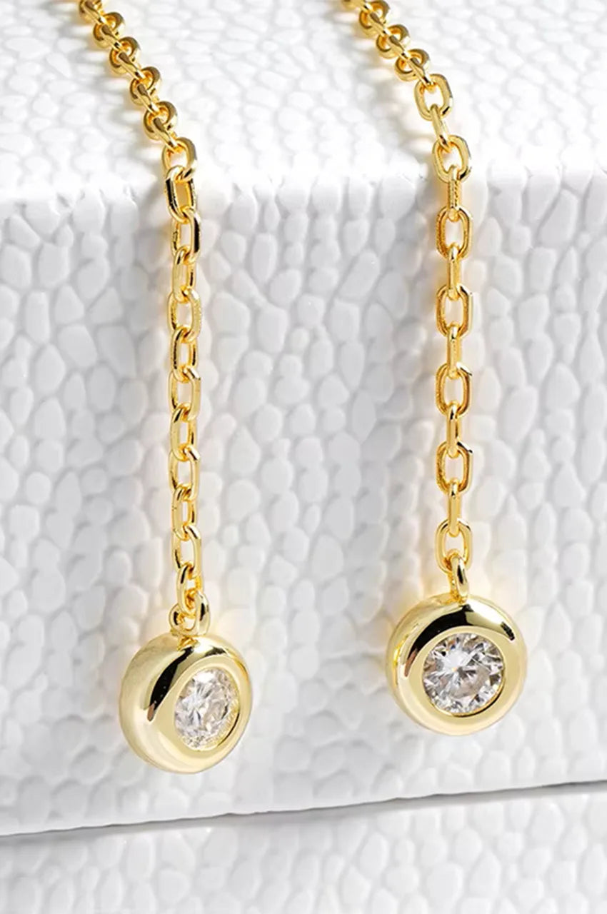 Macro shot of gold chain ends with round bezel set moissanite stones