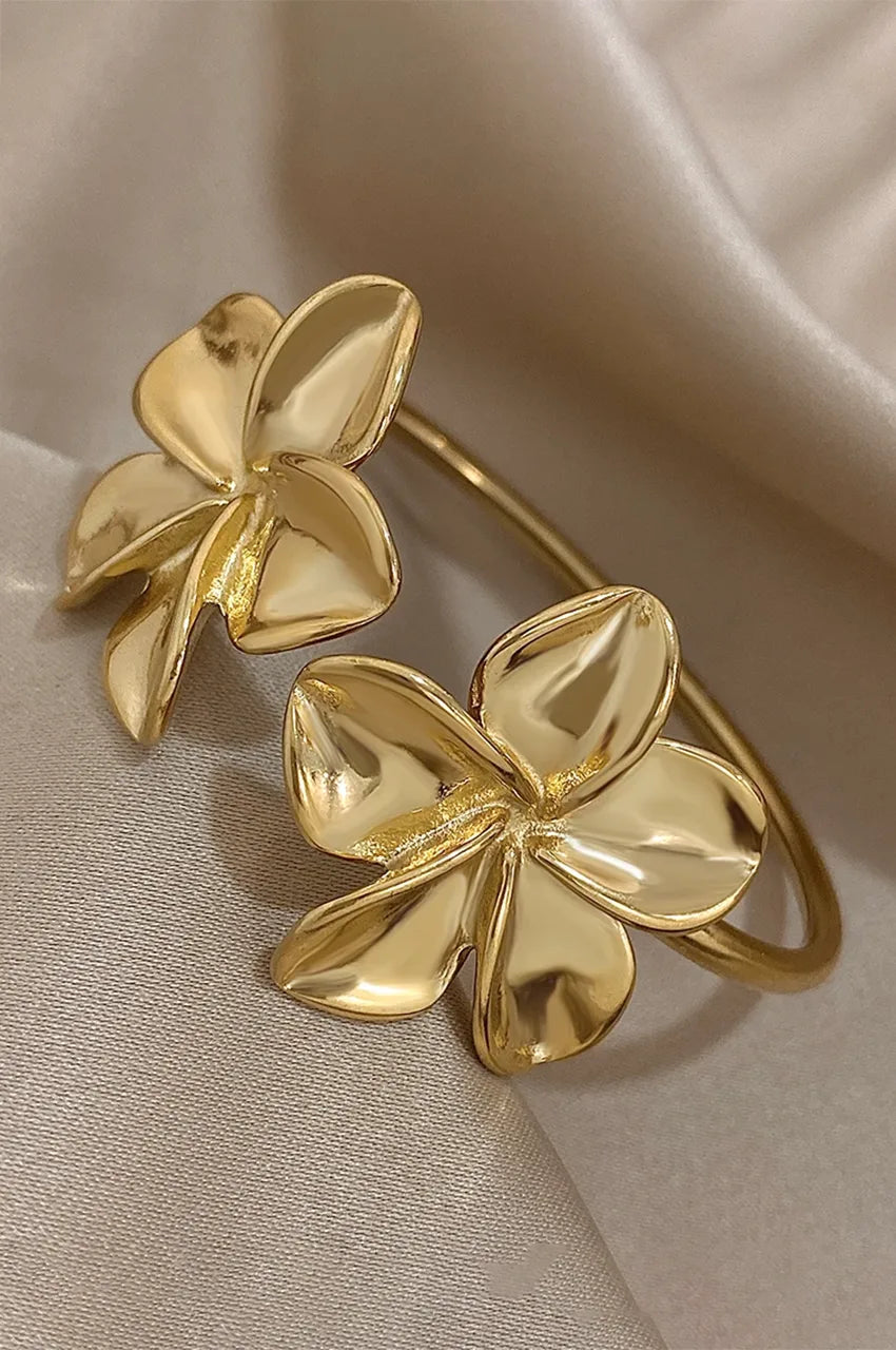 Close up of sculpted gold flower petals on an open cuff bangle.