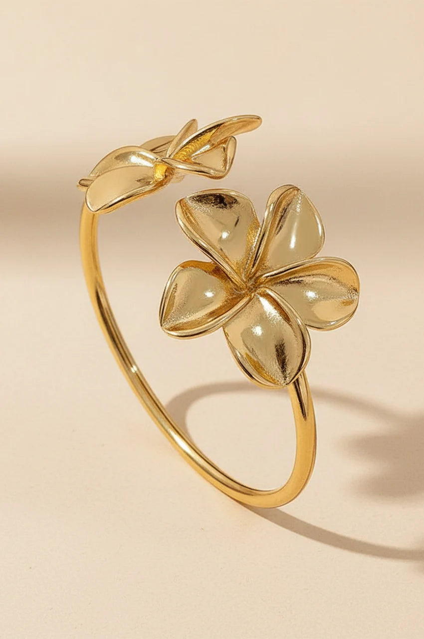 Gold open cuff bracelet with two large flower blossoms standing upright.