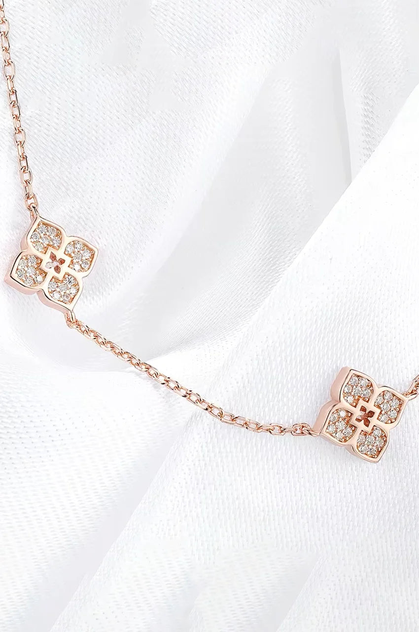 Macro shot of pave moissanite setting on gold four-petal flower necklace