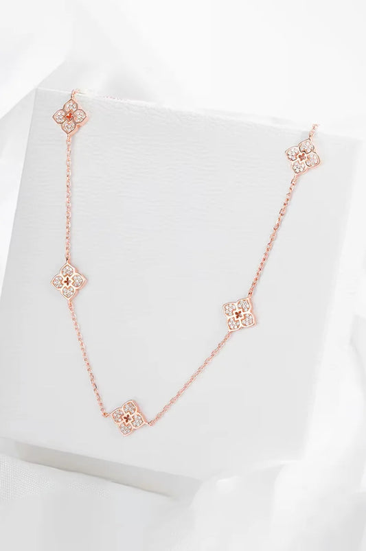 Elegant gold floral necklace displayed on white jewelry box