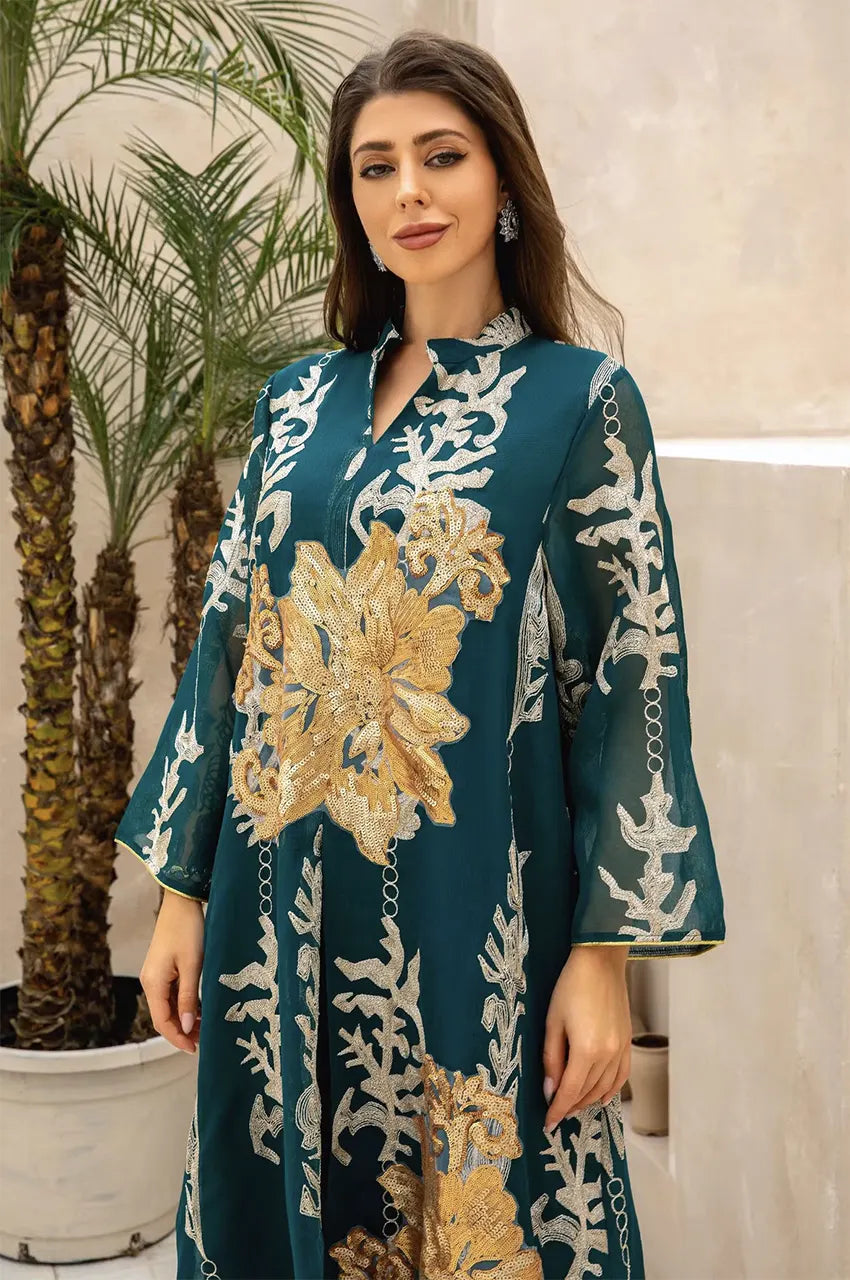 Close-up detail of the gold sequin flower motif and V-neckline on the emerald green Maliya kaftan.