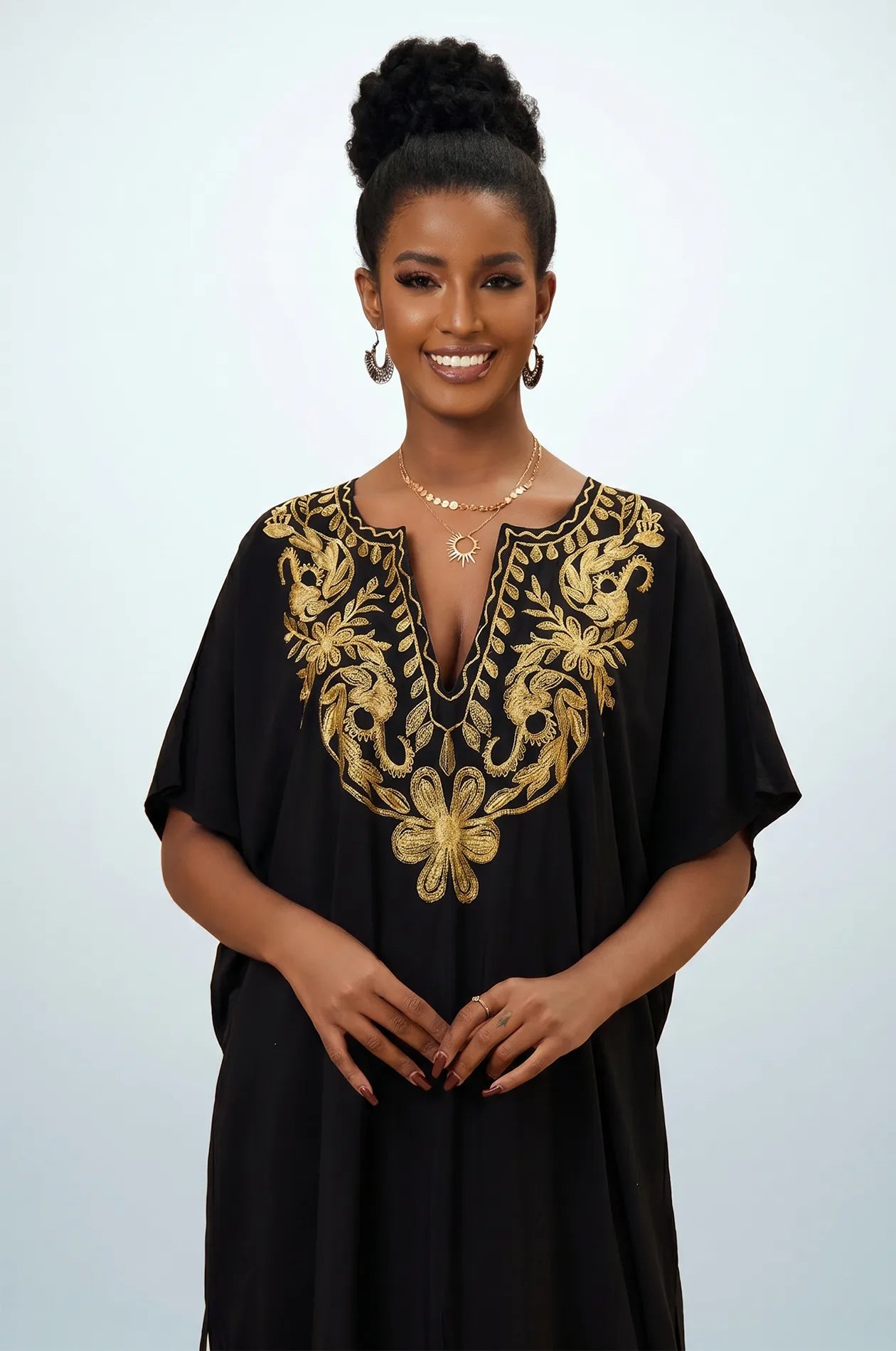 Naylara Halia black gold kaftan with floral chest and hem embroidery — hand on hip studio