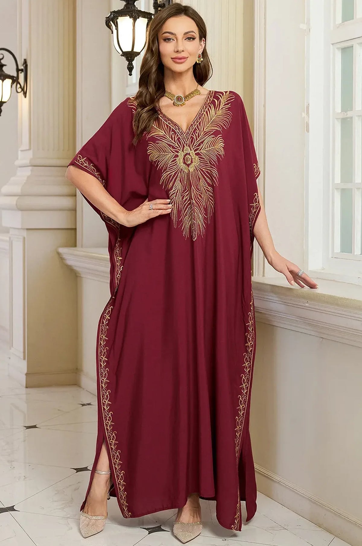 Naylara Laurel red beach kaftan gold feather chest embroidery — hands on hips palace setting