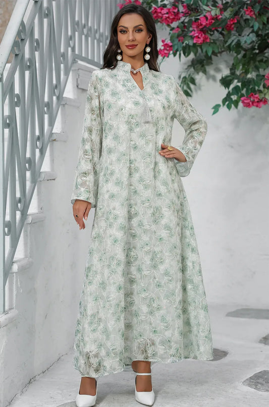 Lifestyle shot of the light green Lyana kaftan near a white staircase.