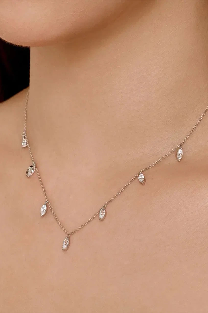 Model wearing delicate sterling station necklace with dangling marquise crystals on bare neck