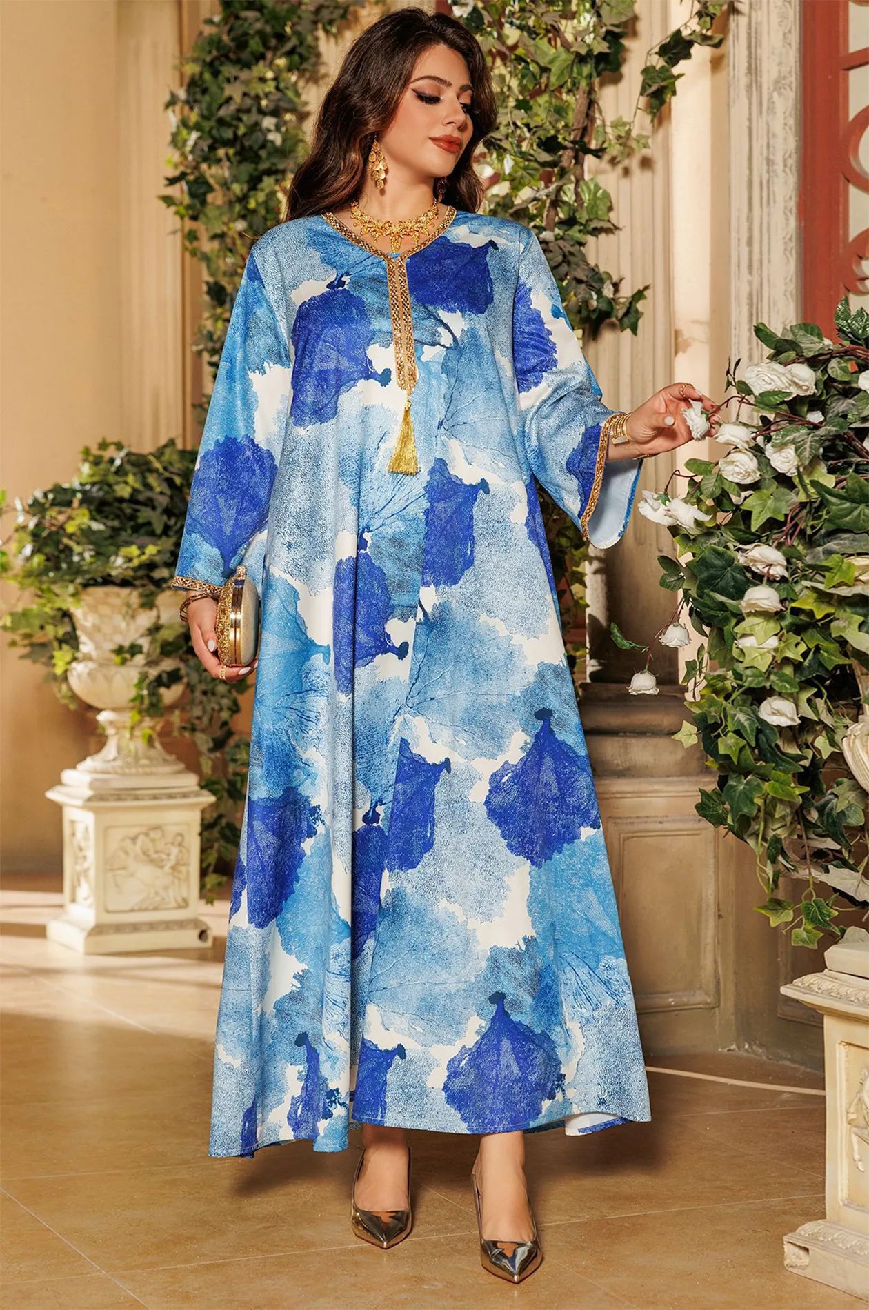 Full shot of the Navae blue tropical print kaftan styled for a summer garden party.