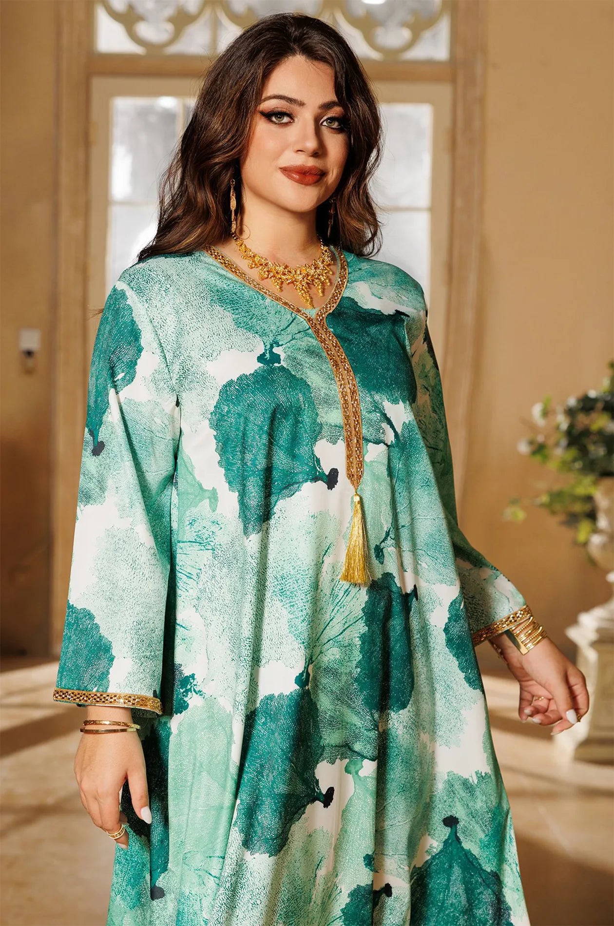 High-fashion portrait detail of the green Navae tropical print kaftan highlighting the luxurious metallic gold embroidery.