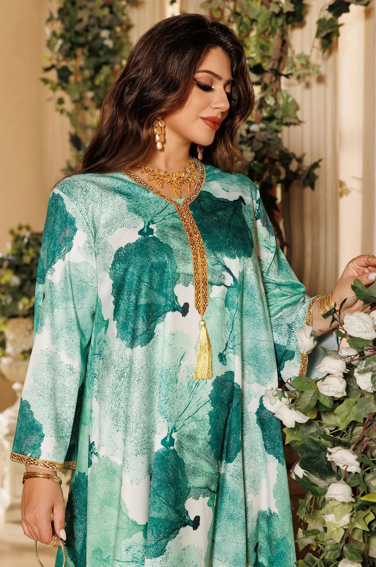 The green Navae tropical print kaftan styled in a botanical garden setting, emphasizing its vibrant summer leaf pattern.