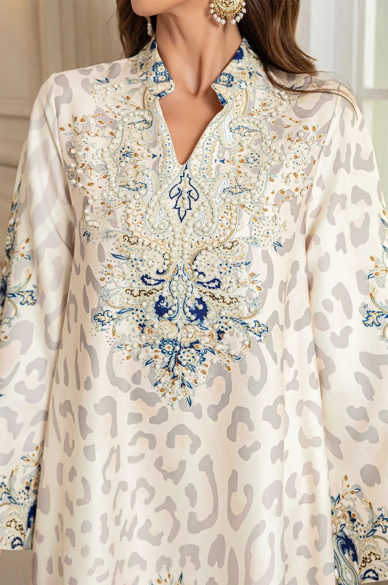 Macro detail of the Nyx White Kaftan’s bodice, showcasing hand-applied pearls, beads, and rhinestones on an intricately embroidered V-neckline.