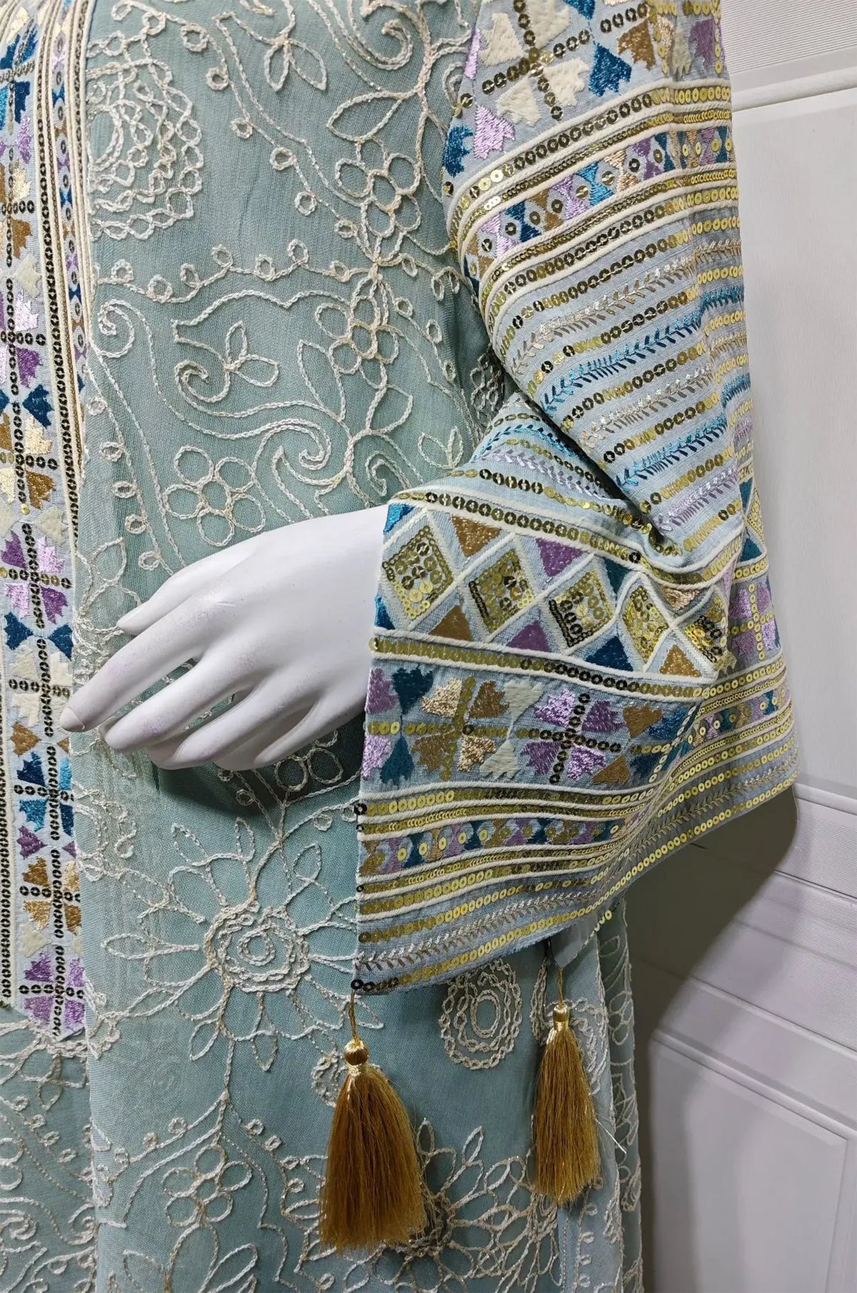 Extreme close-up of the Orla light green kaftan sleeve featuring metallic sequins, geometric lace, and silk tassels.