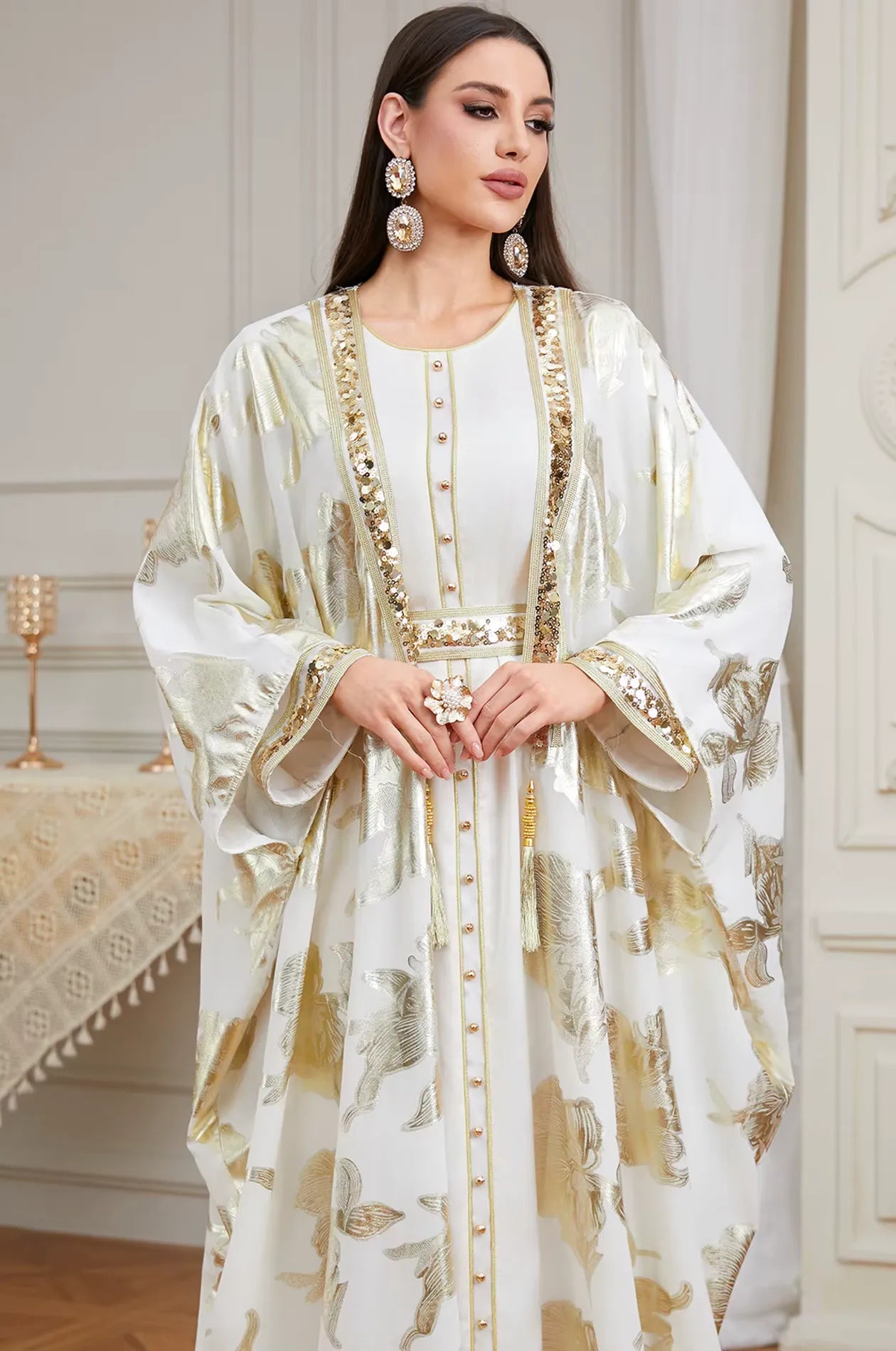 Detailed waist-up view of the white Puppis kaftan luxe focusing on the gold buttons and sequined borders.