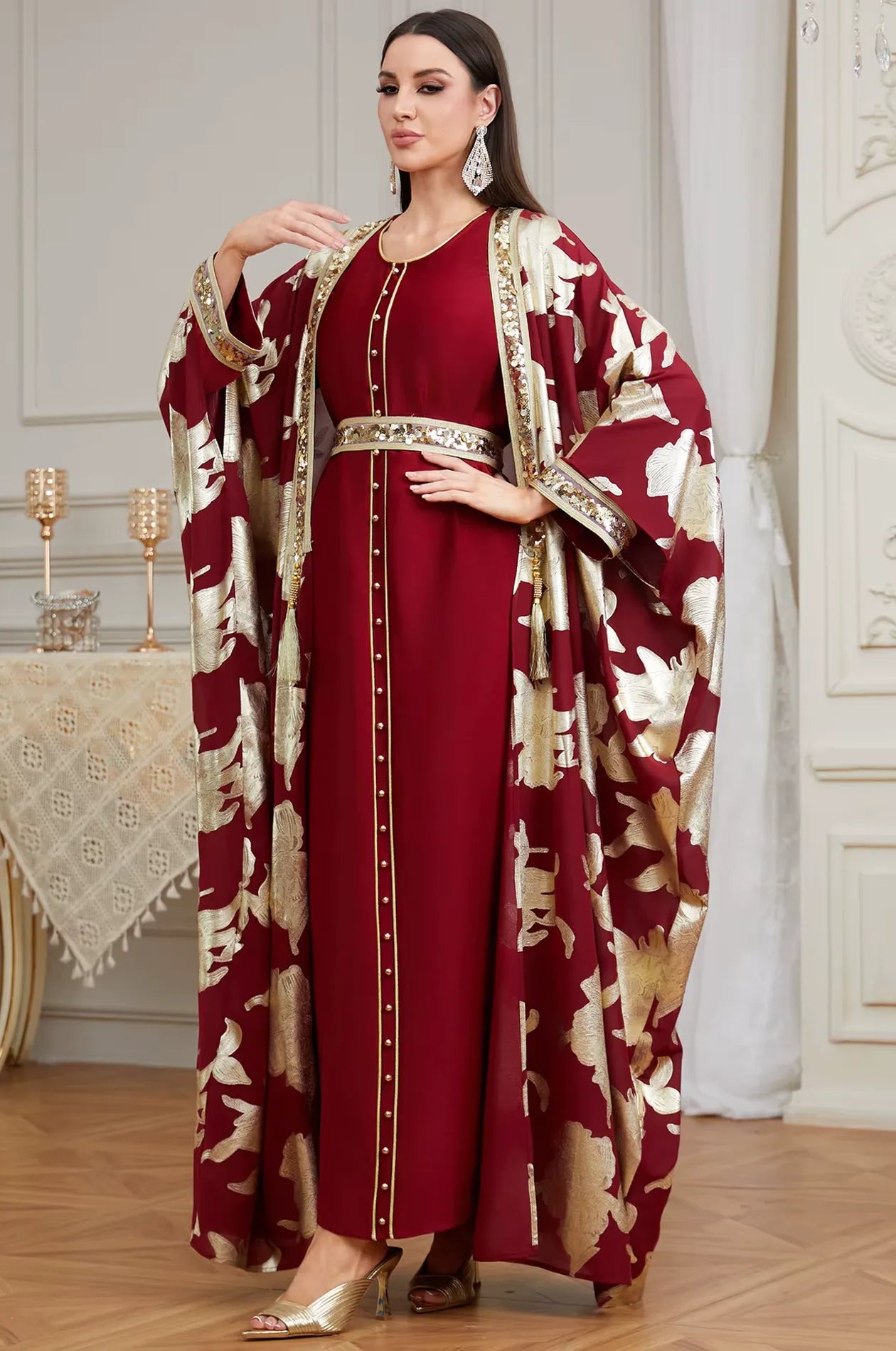 Full-length fashion shot of the red Puppis kaftan luxe by Naylara featuring hand-placed sequins and metallic gold floral brocade.