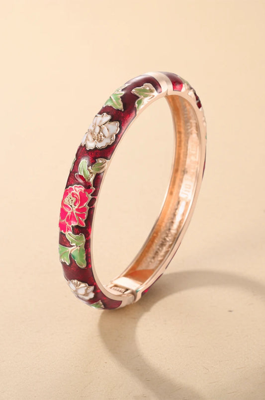 Standing gold-tone bangle bracelet with red enamel and pink flower design.