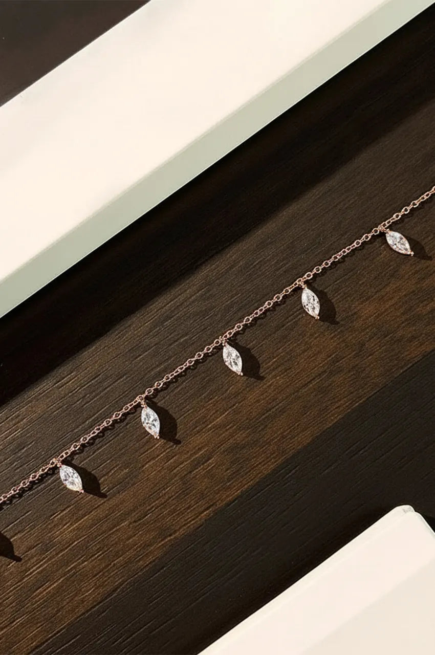 Rose gold diamond stimulant drop necklace displayed on dark wood texture