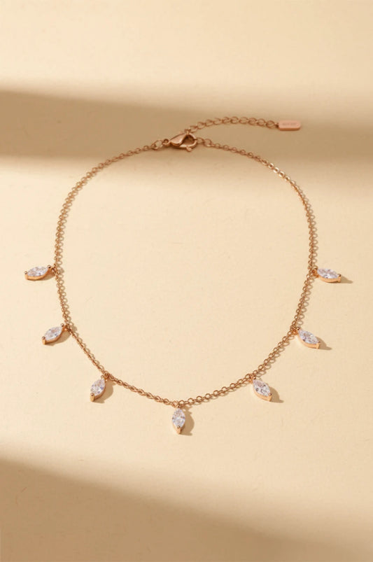 Full view of adjustable rose gold drop necklace on beige background