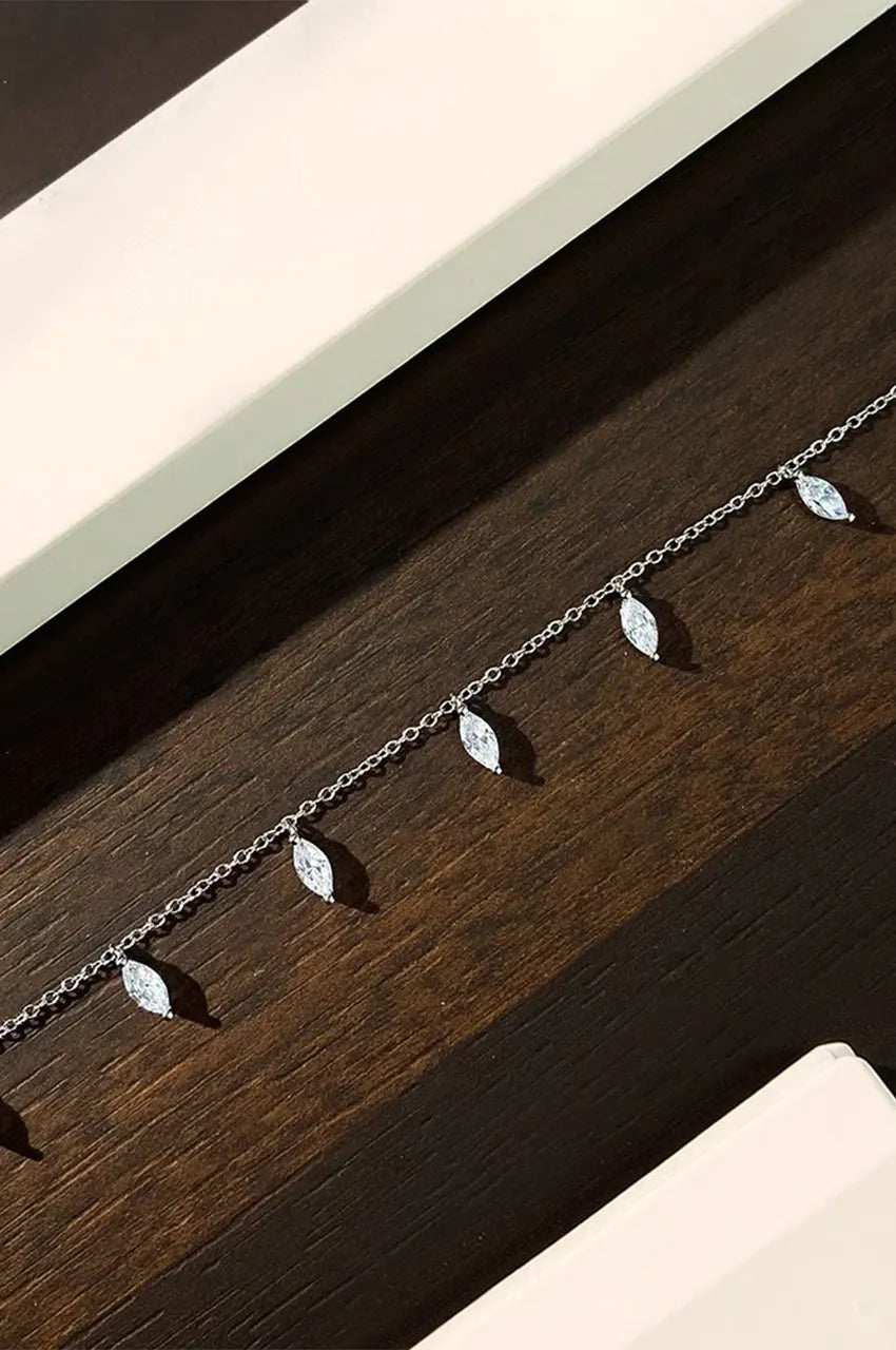 Silver chain choker necklace featuring sparkling marquise-cut stones against a dark, textured background.