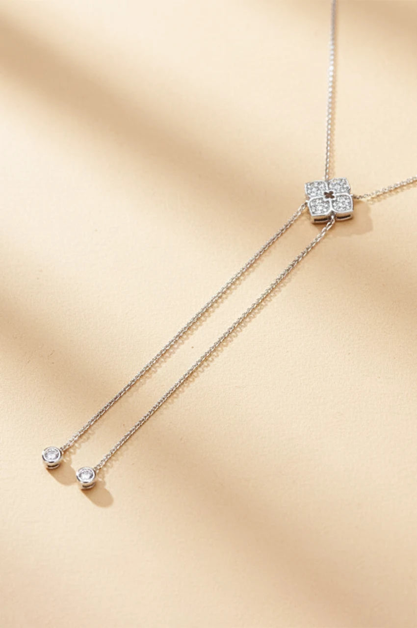 Full view of sterling silver moissanite lariat necklace on beige background
