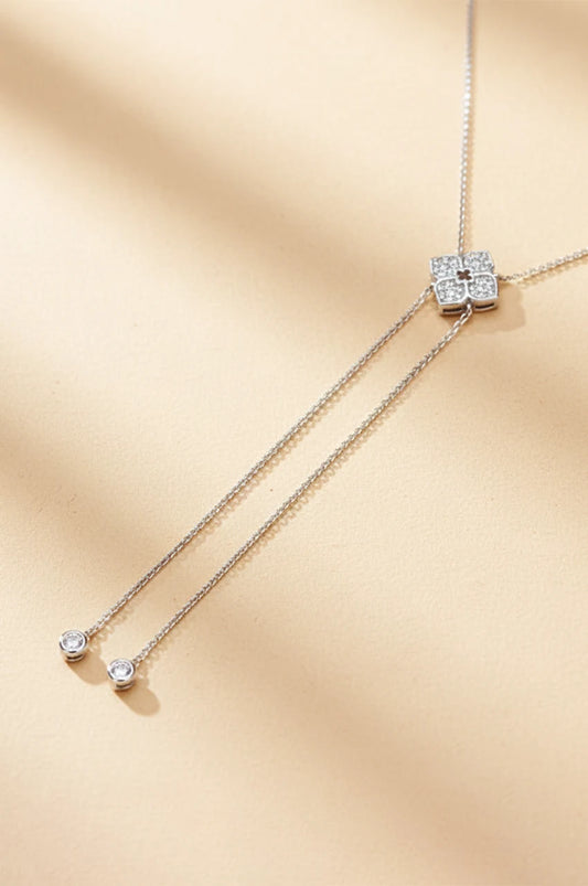 Full view of sterling silver moissanite lariat necklace on beige background