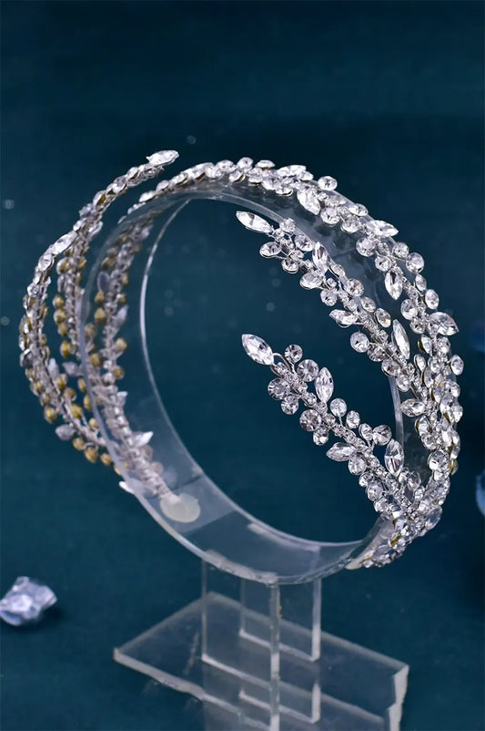 Silver Crystal Wedding Headpiece displayed in a circular shape on a clear acrylic stand against a dark background, showing its vine-like construction.