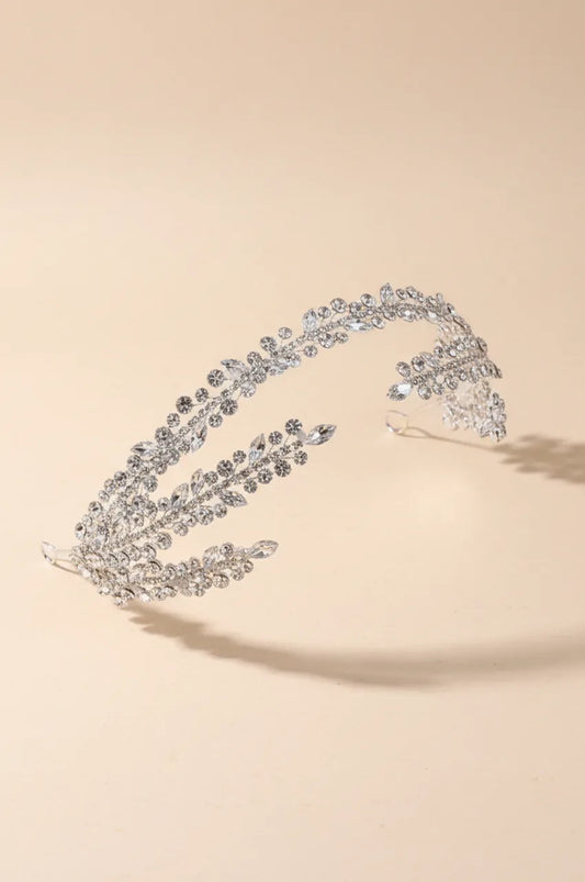 Isolated shot of the flexible Silver-Tone Bridal Headpiece on a cream background, showcasing its open-back shape and delicate rhinestone leaf design.