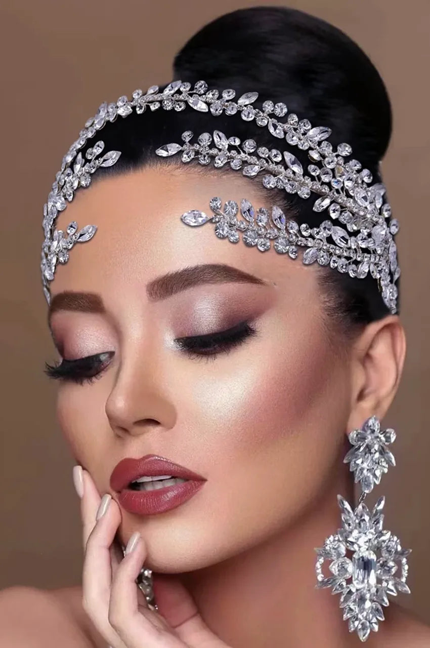 Close-up of Silver Crystal Headpiece worn by a model with a high bun, showcasing the elegant fit along the hairline and matching oversized crystal dangle earrings.
