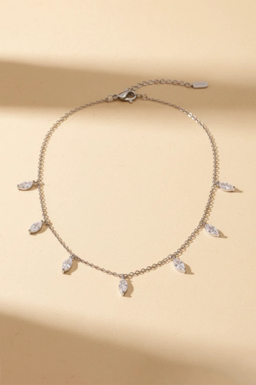 Full view of silver marquise shaker necklace on beige background