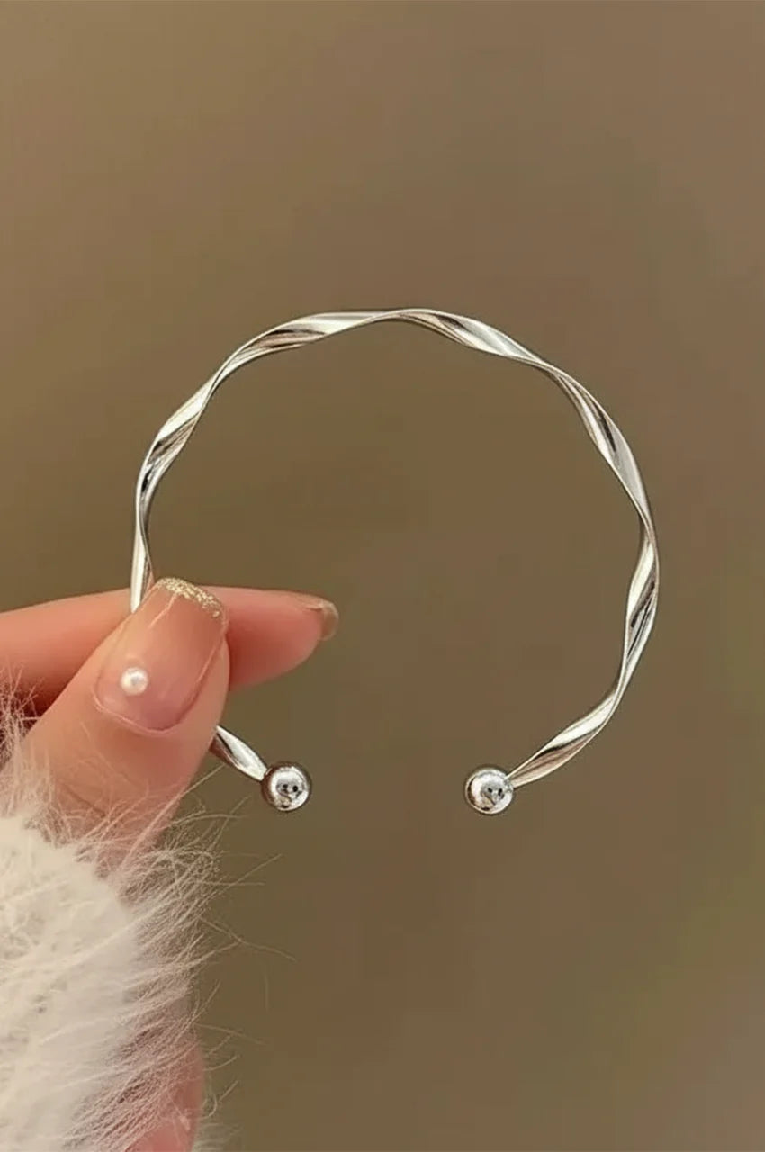 Close up of silver twisted bangle held in hand showing polish.